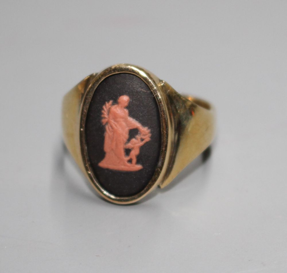 A yellow metal and oval Wedgwood plaque set ring, decorated with a lady and cherub,